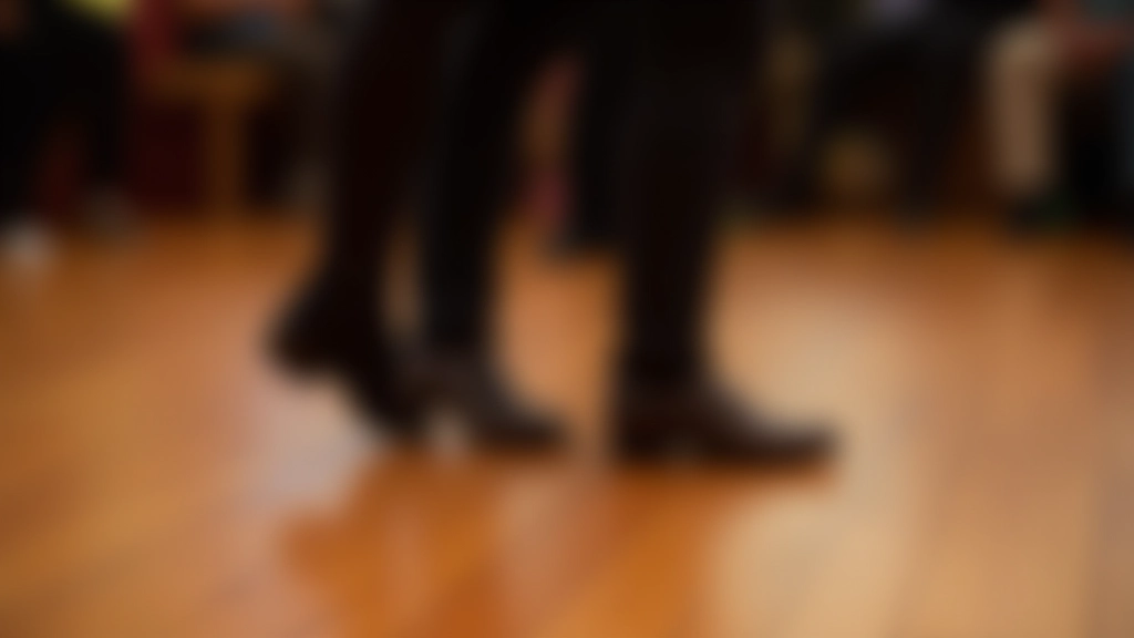 Close-up of feet showing basic bachata step position on wooden dance floor, proper stance from ground perspective